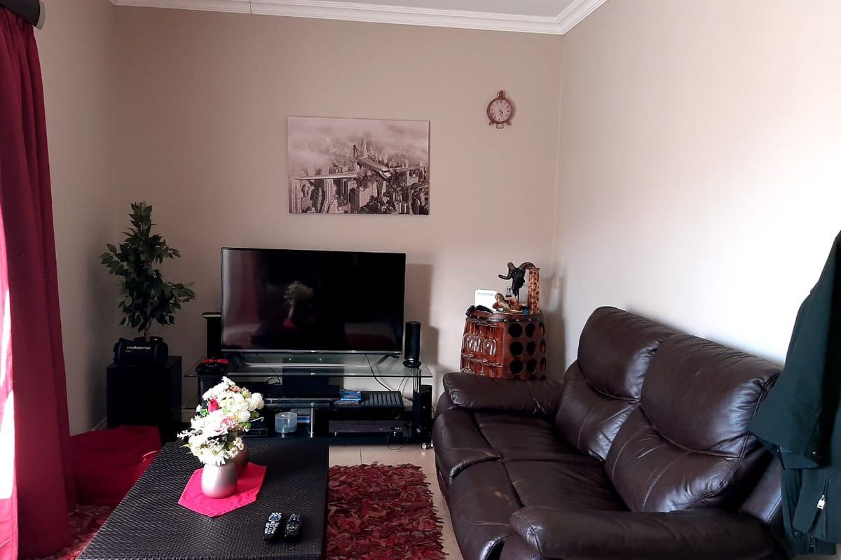 A cozy living room featuring neutral wall tones, crown molding, and tiled flooring, providing a comfortable and functional space for relaxation.