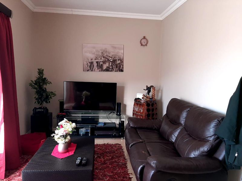 A cozy living room featuring neutral wall tones, crown molding, and tiled flooring, providing a comfortable and functional space for relaxation.