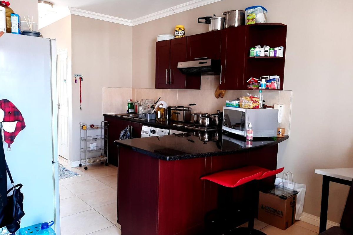 A functional kitchen featuring dark wood cabinetry, granite countertops, a breakfast bar, and tiled flooring, providing a practical layout for daily use.
