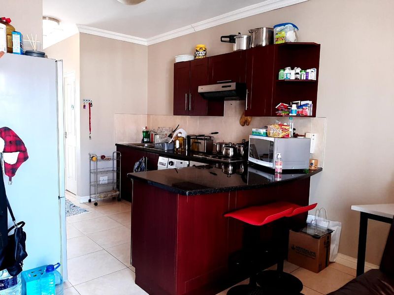 A functional kitchen featuring dark wood cabinetry, granite countertops, a breakfast bar, and tiled flooring, providing a practical layout for daily use.
