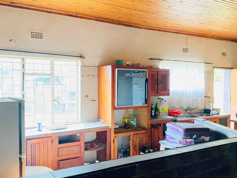 A dated kitchen featuring timber ceilings, built-in wooden cabinetry, and a built-in oven, offering significant potential for a modern renovation.