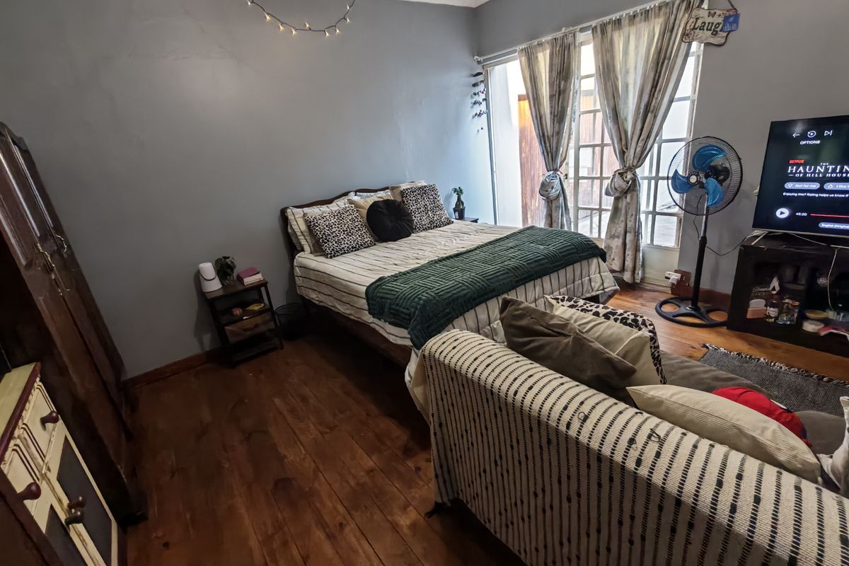 A bedroom featuring hardwood flooring, crown molding, and french doors providing access to the exterior.
