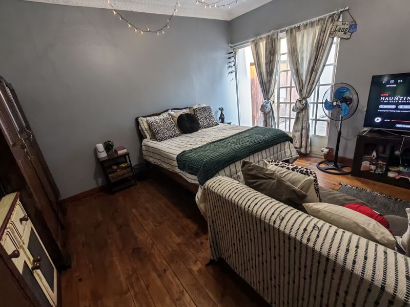 A bedroom featuring hardwood flooring, crown molding, and french doors providing access to the exterior.