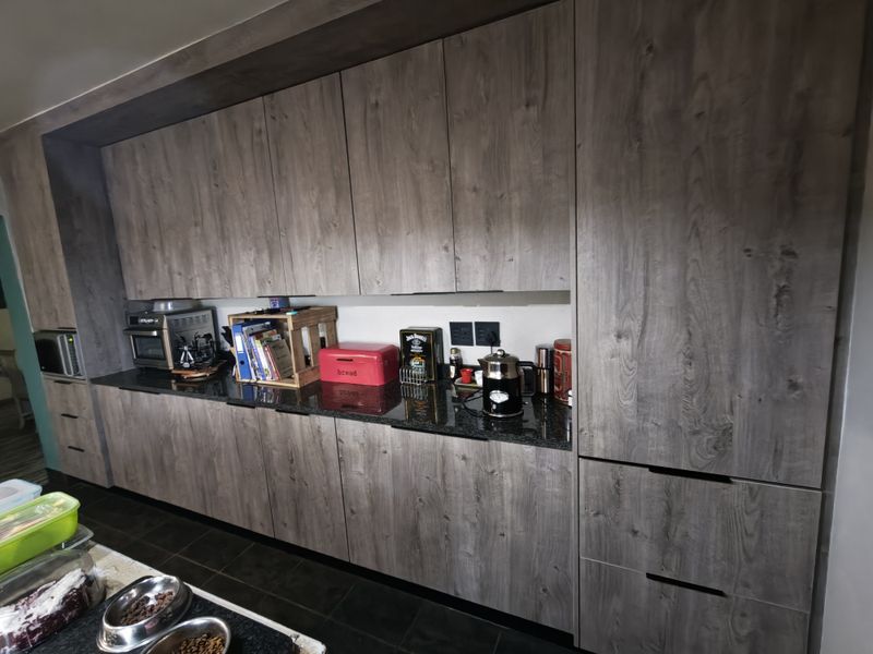 Modern kitchen featuring dark wood-grain cabinetry, sleek granite countertops, and integrated appliances, offering a contemporary and functional workspace.