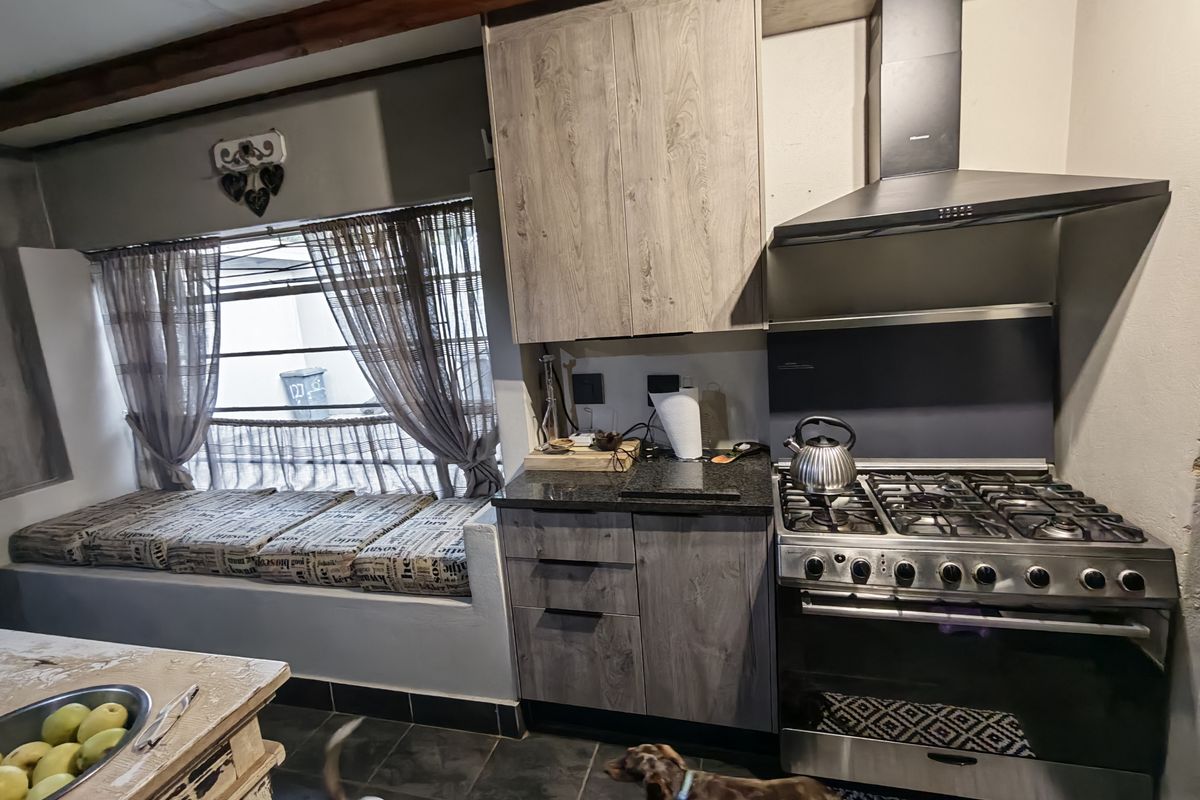 A functional kitchen featuring wood-look cabinetry, granite countertops, a gas stove with extractor fan, and a built-in window seat area.