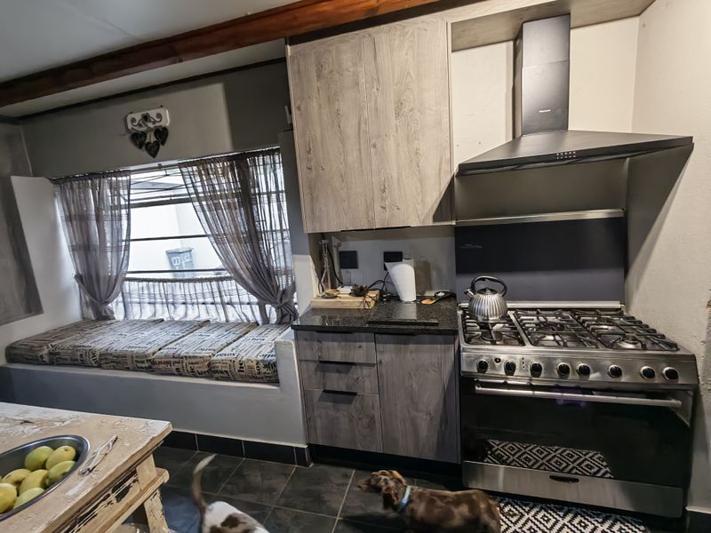 A functional kitchen featuring wood-look cabinetry, granite countertops, a gas stove with extractor fan, and a built-in window seat area.
