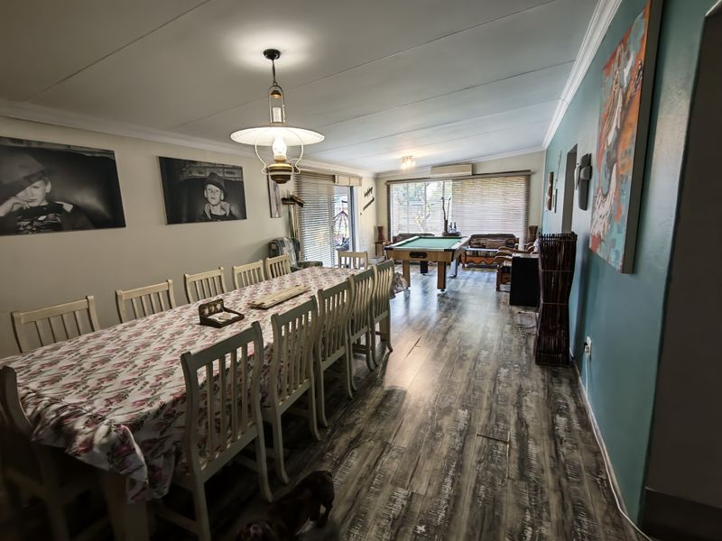 Spacious open-plan living and dining area featuring wood-look laminate flooring, coved ceilings, and a split-system air conditioner for climate control.