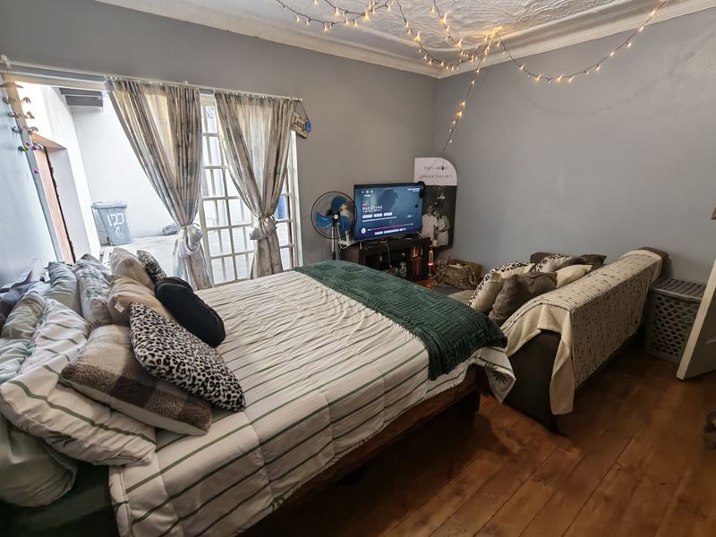 A bedroom featuring hardwood flooring, decorative ceiling molding, and french doors providing access to an outdoor area.