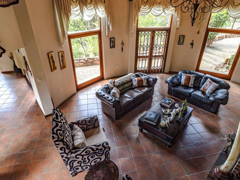 Spacious living room featuring terracotta tiled flooring, a brick fireplace, and large windows providing ample natural light and access to the outdoor area.