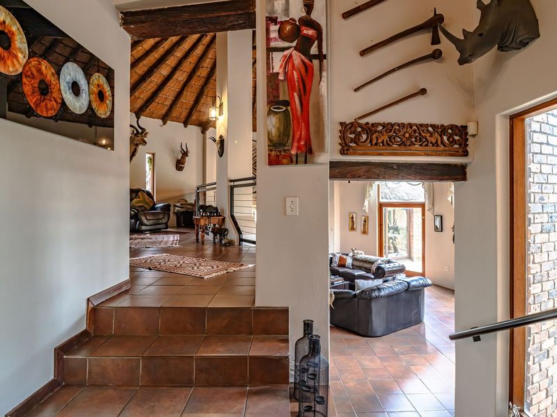 An inviting entryway featuring tiled flooring, exposed timber beams, and a unique thatched ceiling, leading into a spacious open-plan living area.