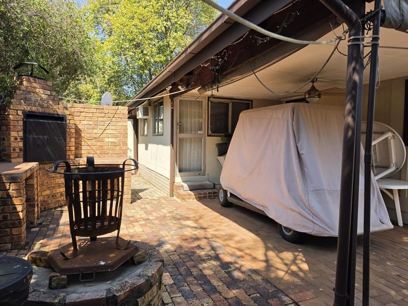 Outdoor paved patio area featuring a built-in brick braai and a covered entertainment space, ideal for casual outdoor dining and relaxation.