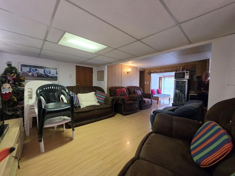 Open plan living area featuring wood-look laminate flooring, wood paneling, and a drop ceiling with recessed lighting.