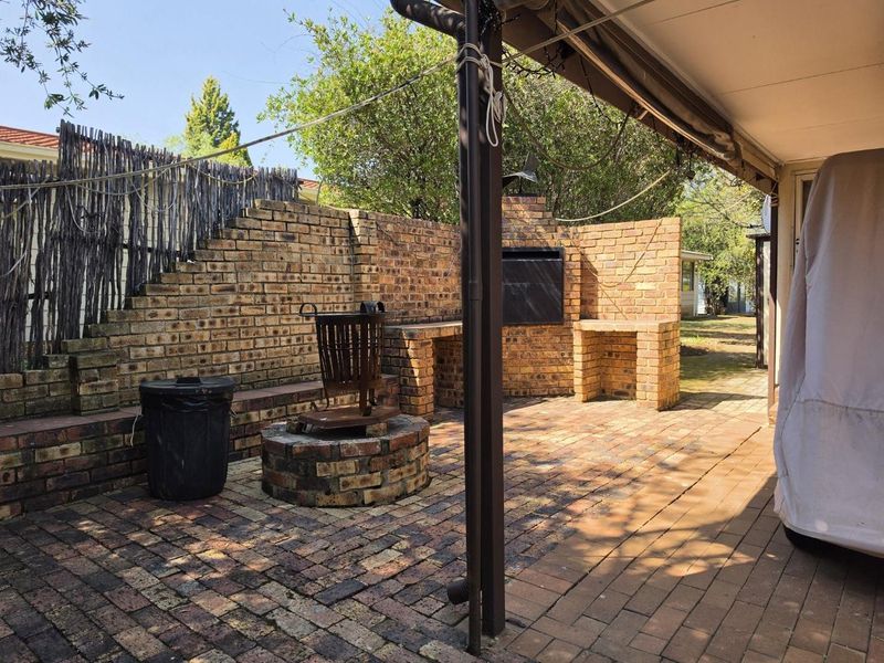 A covered outdoor patio area featuring a built-in brick braai and paved flooring, ideal for outdoor entertaining.