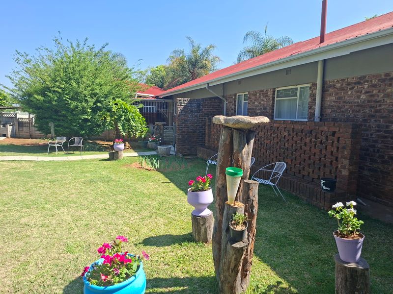 A view of the rear exterior featuring a face brick facade, a red corrugated metal roof, and a well-maintained lawn area.