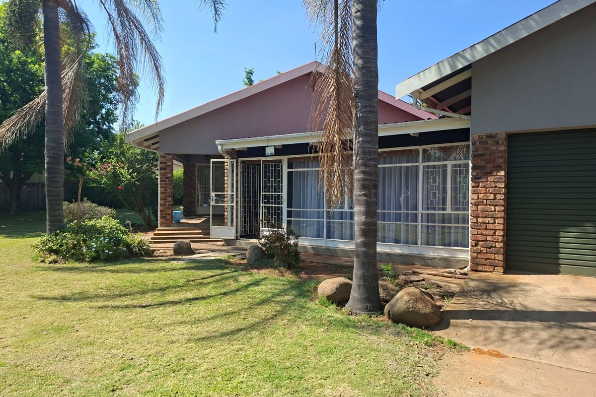 Rear view of the house featuring a brick facade, large glass sliding doors with security gates, a concrete patio, and a metal roller garage door.