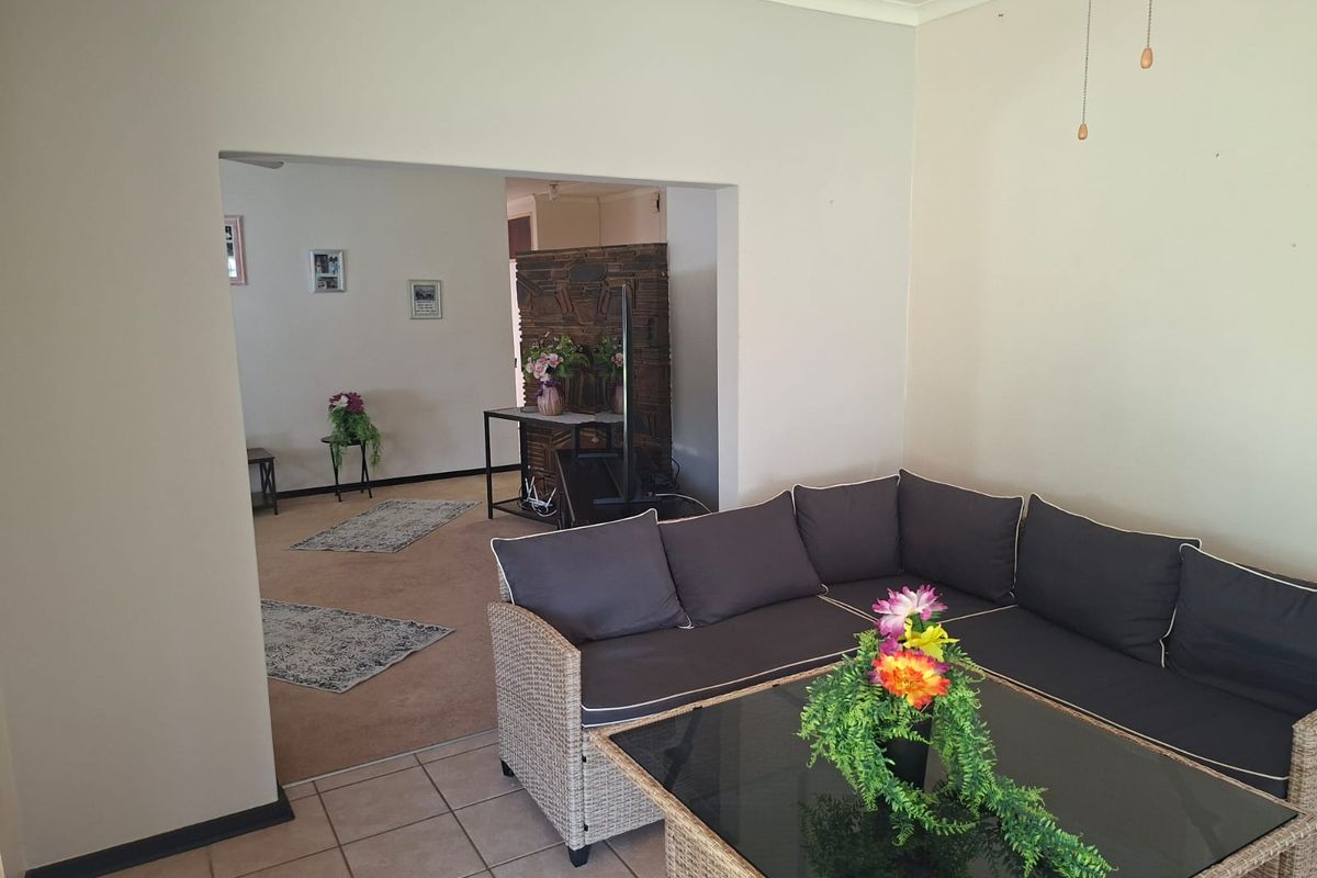 A living room area featuring a combination of tiled and carpeted flooring with an open-plan layout leading to an adjacent space.