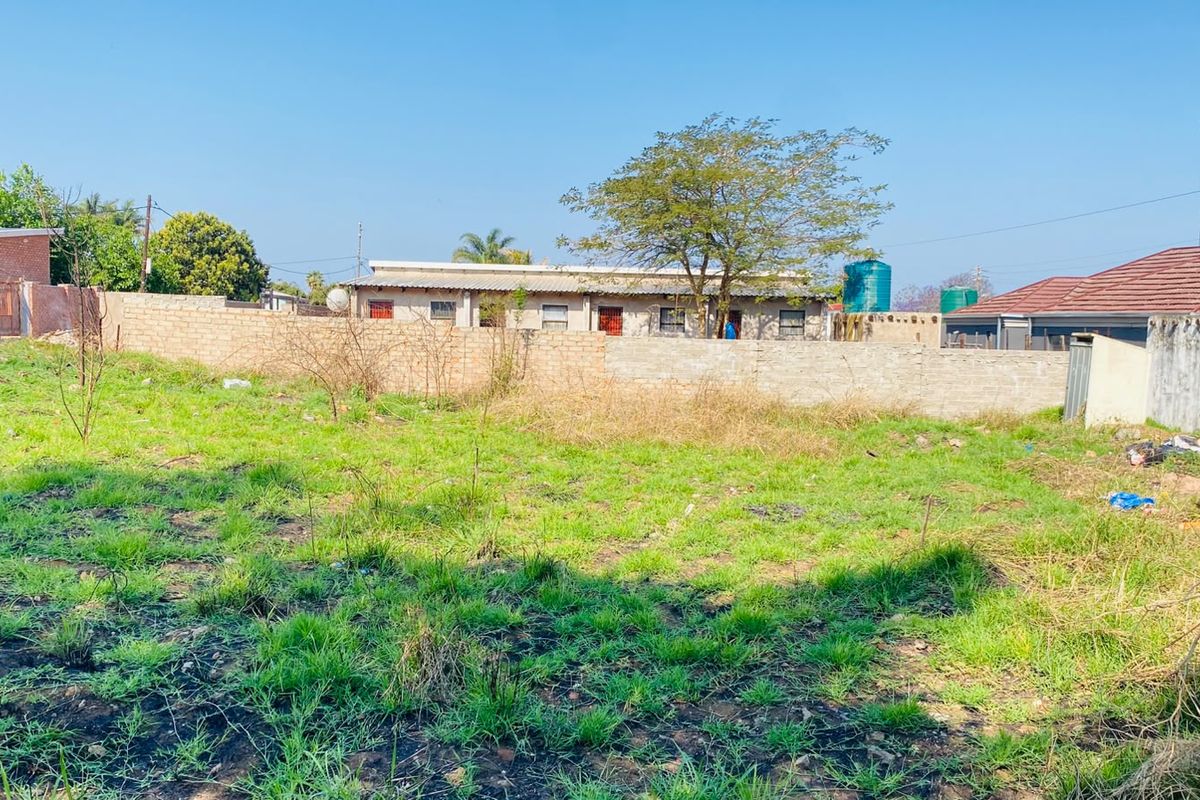 A view of a vacant residential plot featuring a perimeter brick wall and existing water storage infrastructure.