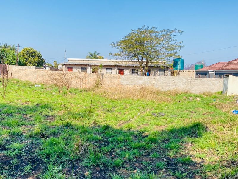 A view of a vacant residential plot featuring a perimeter brick wall and existing water storage infrastructure.