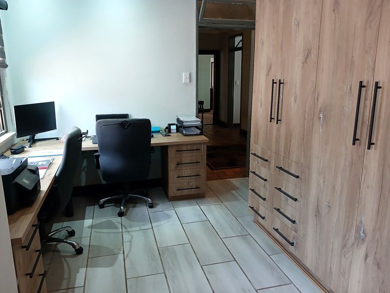 A functional home office featuring built-in wooden cabinetry, a matching desk, and modern tiled flooring, providing a clean and organized workspace.