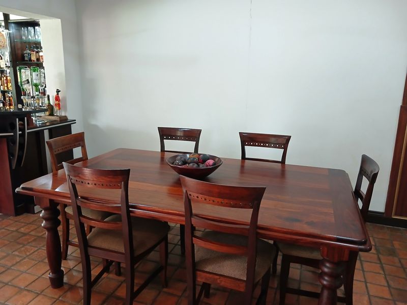 A dining room featuring terracotta tile flooring and an adjacent built-in bar area.