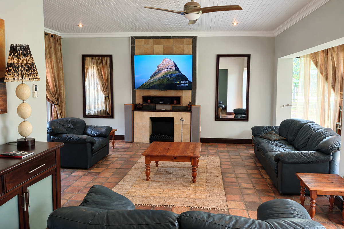 A spacious living room featuring a central tiled fireplace, terracotta flooring, and a classic tongue and groove ceiling with a fitted fan.