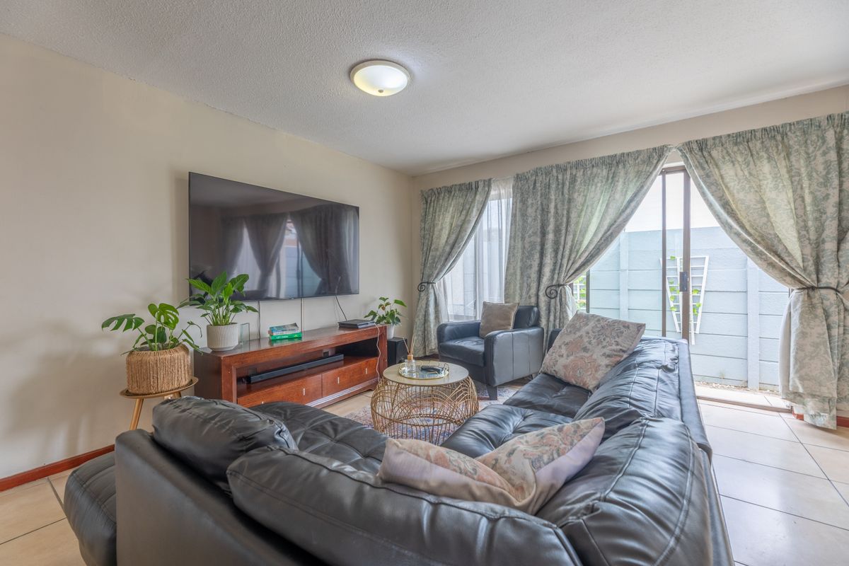 A comfortable living room featuring ceramic floor tiles and a sliding glass door providing access to the outdoor area.