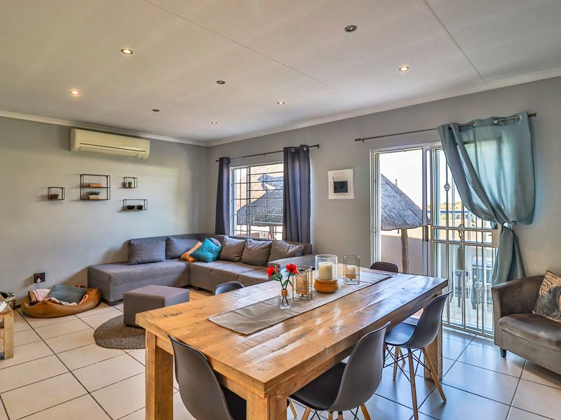 Spacious open-plan living and dining area featuring tiled flooring, recessed lighting, and a split-system air conditioner with direct access to an outdoor space.