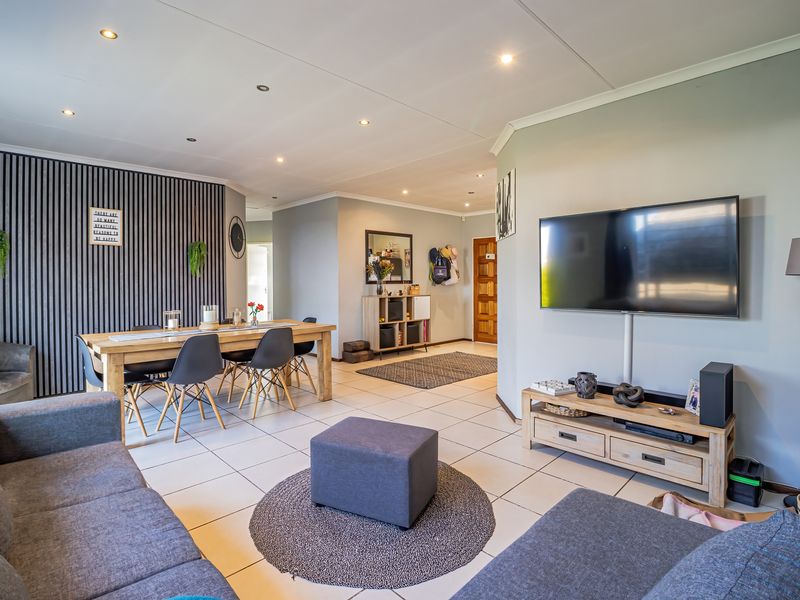 Spacious open-plan living and dining area featuring tiled floors, recessed lighting, and a modern slatted feature wall.