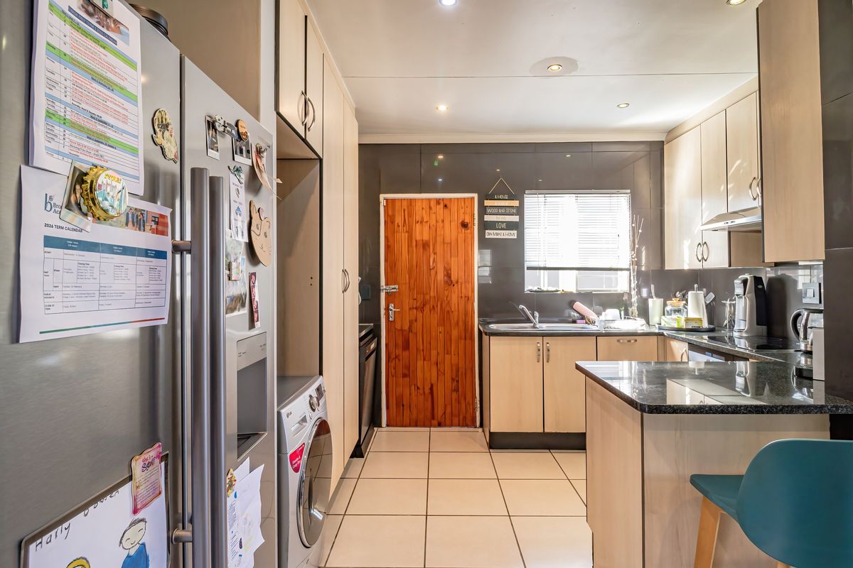 A functional kitchen featuring light wood cabinetry, dark granite countertops, tiled flooring, and integrated appliance spaces, providing a practical and well-lit culinary workspace.