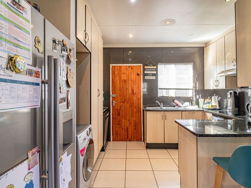 A functional kitchen featuring light wood cabinetry, dark granite countertops, tiled flooring, and integrated appliance spaces, providing a practical and well-lit culinary workspace.