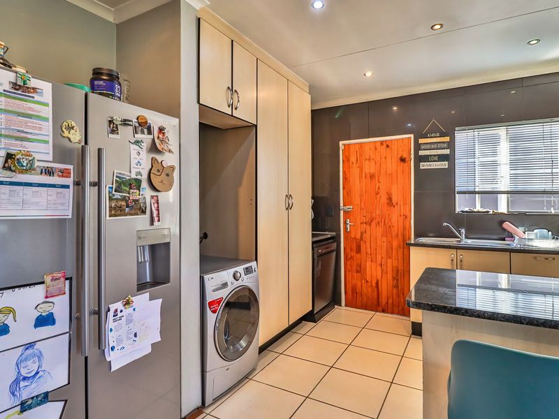 A functional kitchen featuring built-in cabinetry, granite countertops, tiled flooring, and a convenient integrated laundry appliance space.