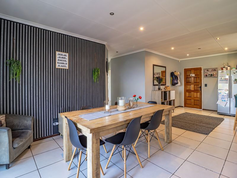 Open-plan dining area featuring tiled flooring, recessed lighting, and a decorative feature wall, creating a functional and inviting living space.