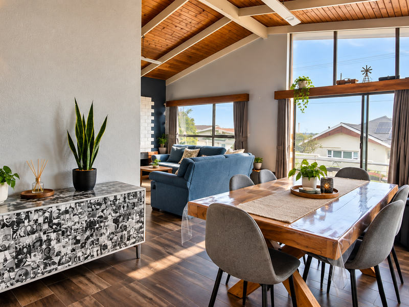 Spacious open-plan living and dining area featuring a vaulted timber ceiling, exposed beams, and large windows that provide abundant natural light.