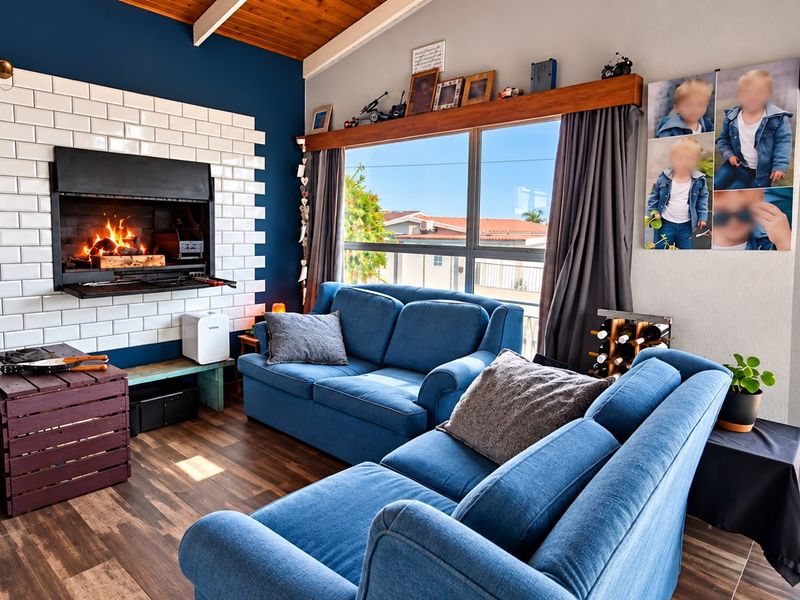 A cozy living room featuring a built-in fireplace with a white subway tile surround, exposed timber ceiling beams, and large sliding doors leading outdoors.