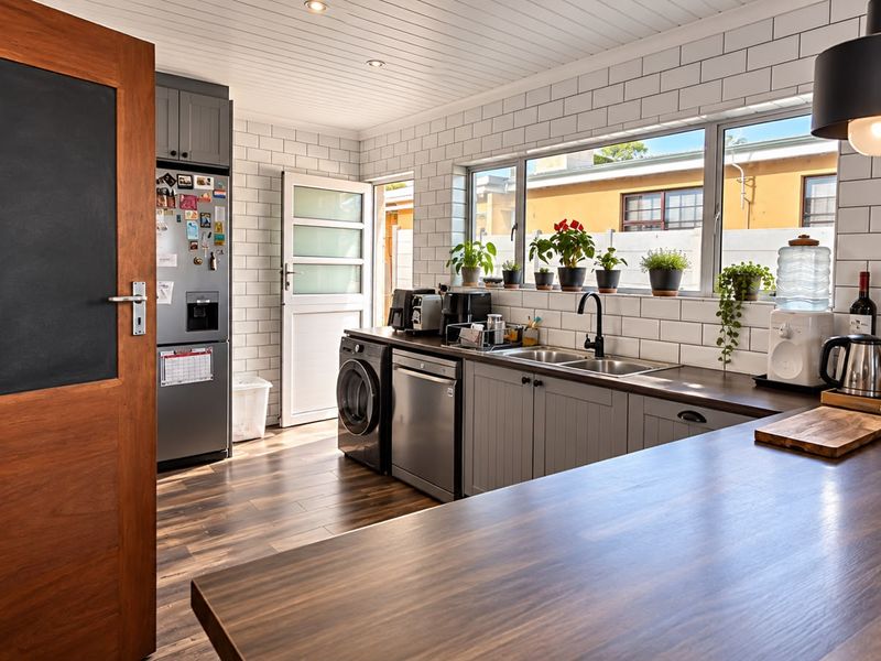 Modern kitchen featuring subway tile backsplash, dark wood-look countertops, stainless steel sink, and integrated cabinetry with recessed and pendant lighting.