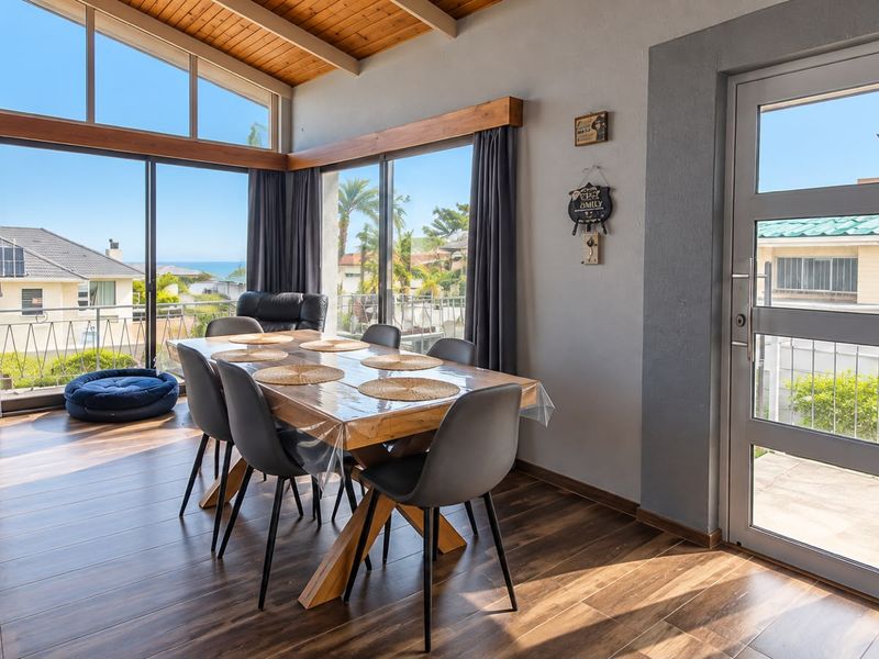 Bright dining area featuring a timber-clad vaulted ceiling, exposed beams, and large sliding doors that provide ample natural light and access to the outdoors.