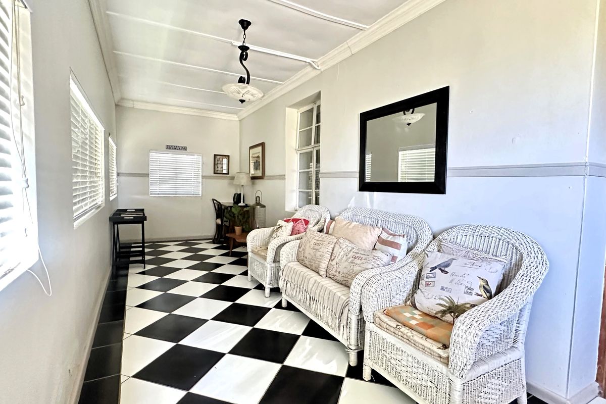 A bright living area featuring distinctive black and white checkered tile flooring, crown molding, and a beadboard ceiling with a central pendant light.