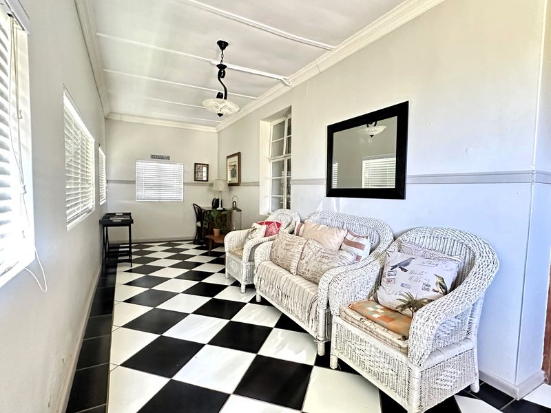 A bright living area featuring distinctive black and white checkered tile flooring, crown molding, and a beadboard ceiling with a central pendant light.