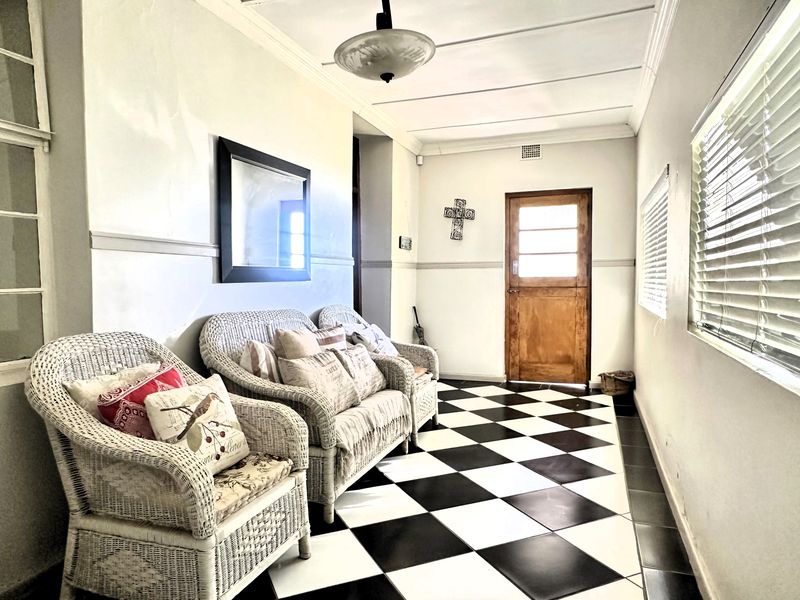 An entrance hall featuring classic black and white checkerboard tile flooring, a wooden door, and crown molding, providing a bright and welcoming transition space.