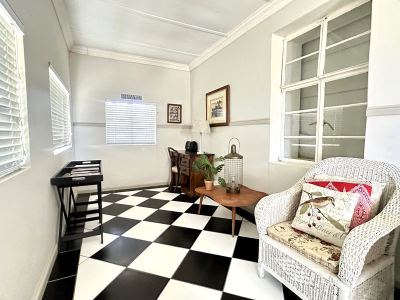 A bright living area featuring classic checkerboard tile flooring, crown molding, and large multi-pane windows that provide ample natural light.