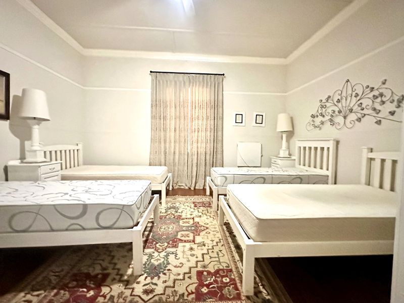 A spacious bedroom featuring high ceilings with coved detailing and a classic picture rail, providing a neutral foundation for various interior design styles.