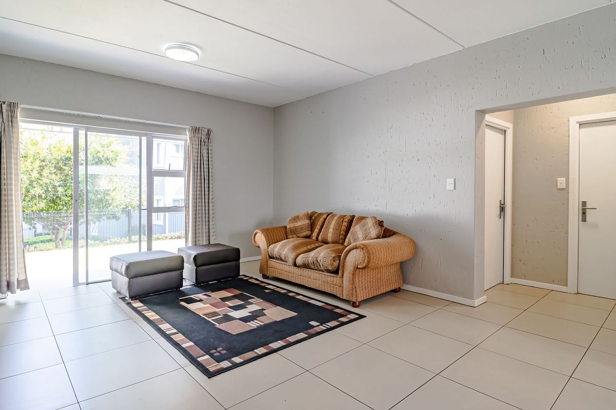 Spacious living room featuring neutral tiled flooring, textured walls, and a large sliding glass door providing access to the outdoor area.