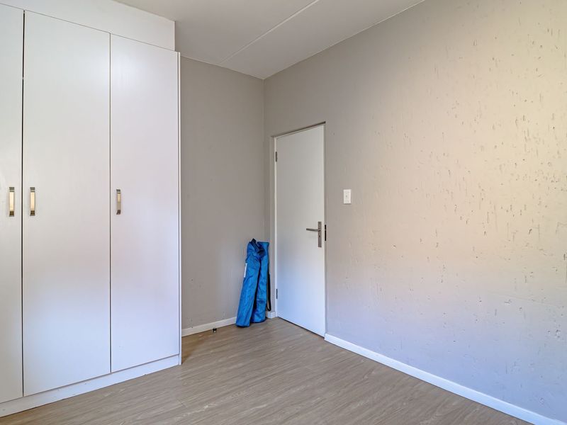 A vacant bedroom featuring built-in cupboards, laminate flooring, and neutral wall finishes, offering a blank canvas for personalization.