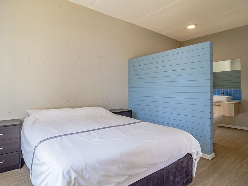 Bedroom featuring a semi-open plan layout with a partition wall separating the sleeping area from a built-in vanity and basin.