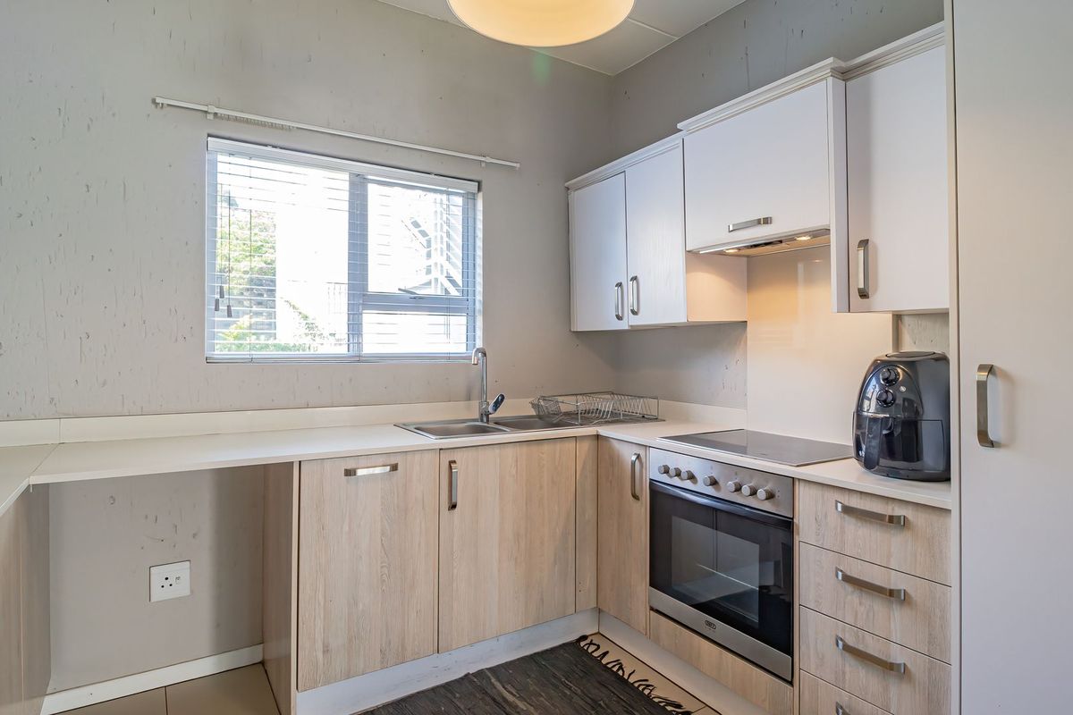 A functional kitchen featuring light wood-look cabinetry, integrated appliances including an oven and hob, and a practical layout with ample counter space.