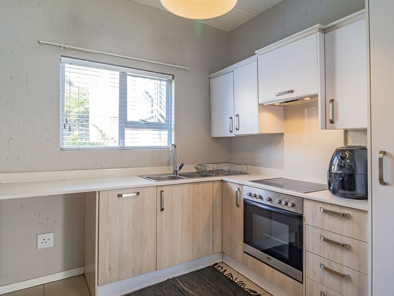A functional kitchen featuring light wood-look cabinetry, integrated appliances including an oven and hob, and a practical layout with ample counter space.
