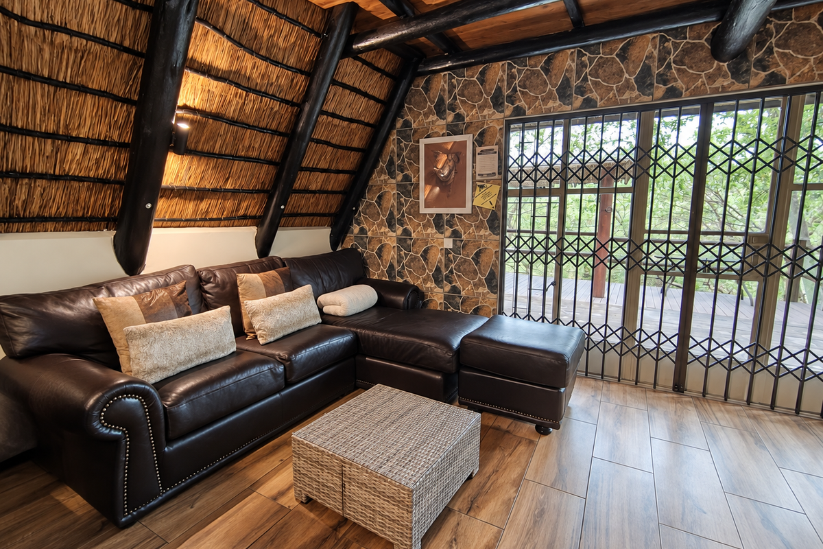 A cozy living room featuring a unique thatched ceiling with exposed timber beams, stone-clad feature wall, and direct access to an outdoor area via security gates.