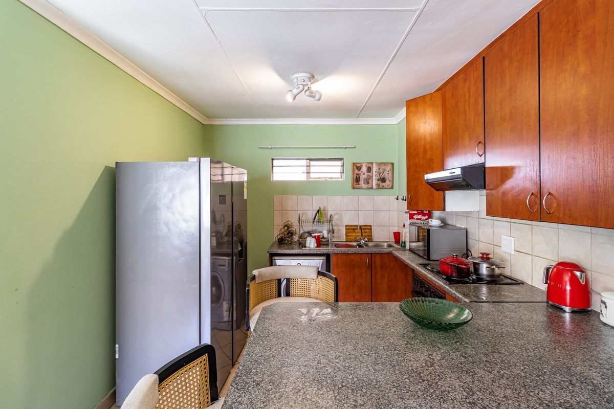 A functional kitchen featuring granite countertops, wooden cabinetry, a tiled backsplash, and an integrated extractor fan, offering a practical layout for daily use.