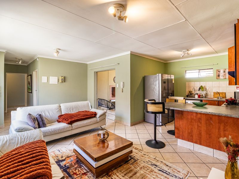 Open plan living and kitchen area featuring tiled flooring, a kitchen island with laminate countertops, and functional cabinetry.