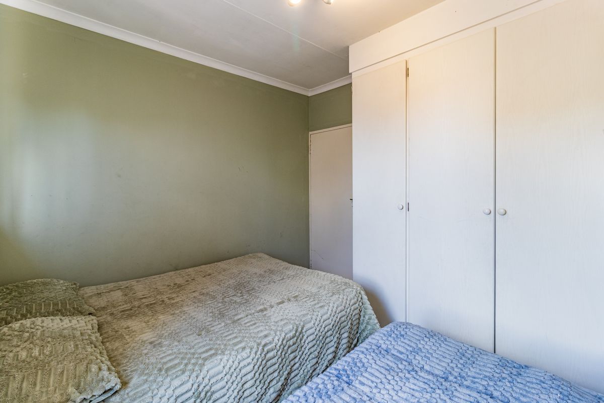 A bedroom featuring built-in cupboards and green painted walls, offering a functional space with standard finishes.